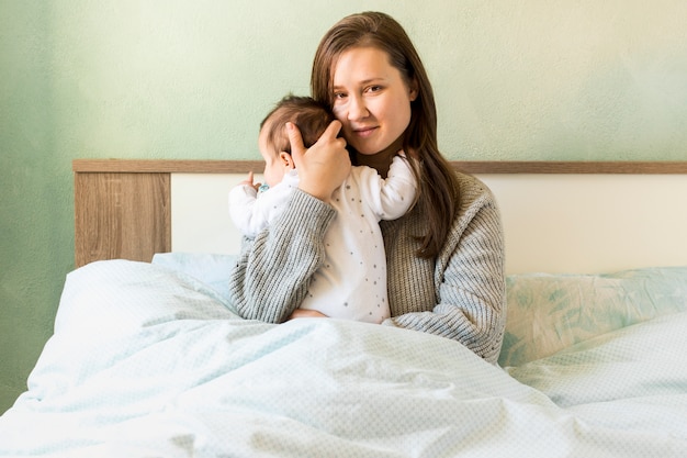 Madre abrazando al bebé en la cama