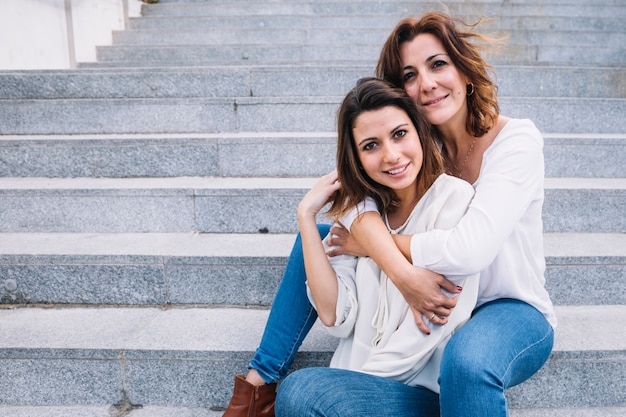 madre abrazando a mujer y mirando a cámara