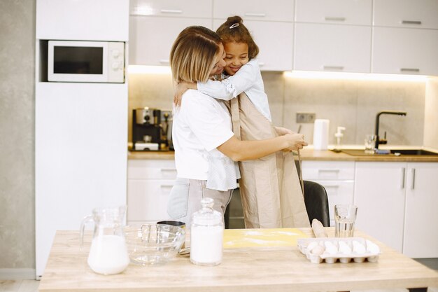 Madre abrazando a su hija. Cuidando a mamá feliz cocinando junto con un niño étnico pequeño