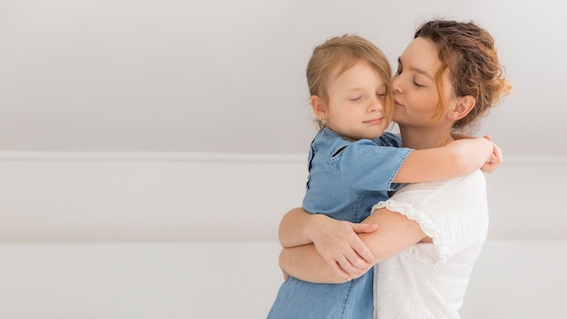 Foto gratuita madre abrazando a su niña en casa