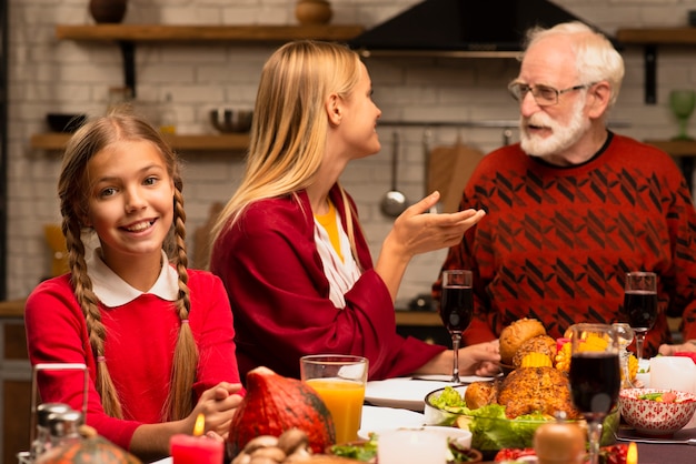 Madre y abuelo conversando e hija mirando a cámara