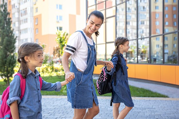 La madre acompaña a los estudiantes a la escuela, los niños con mochilas escolares van a la escuela.