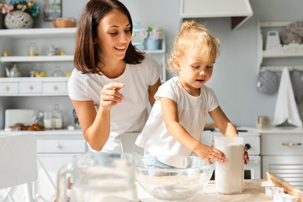 Madre y adorable niña cocinando juntos