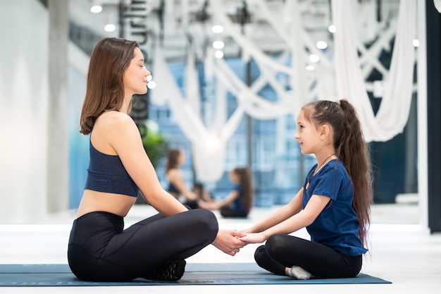 Madre adulta joven y pequeña hija juntas practicando yoga