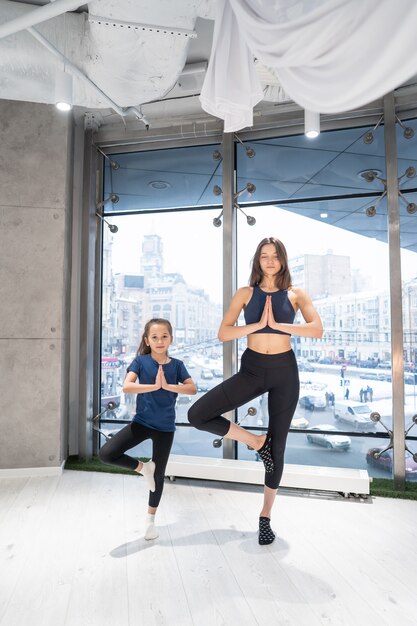 Madre adulta joven y pequeña hija juntas practicando yoga