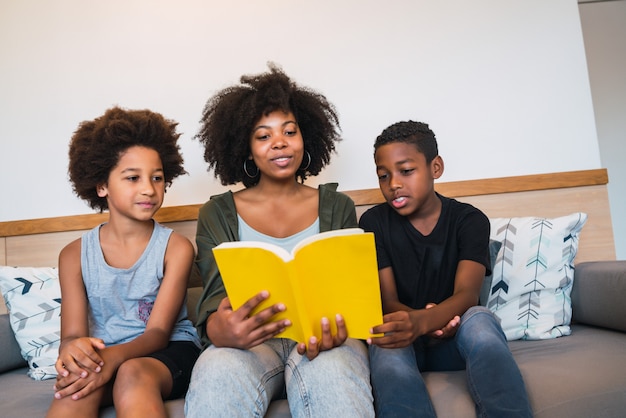 Madre afro leyendo un libro a sus hijos.
