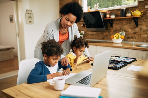 Madre afroamericana ayudando a sus hijos a aprender en casa