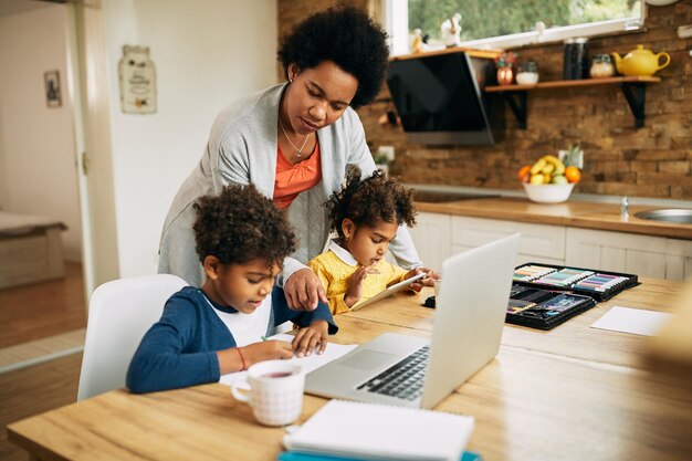 Madre afroamericana ayudando a sus hijos a aprender en casa