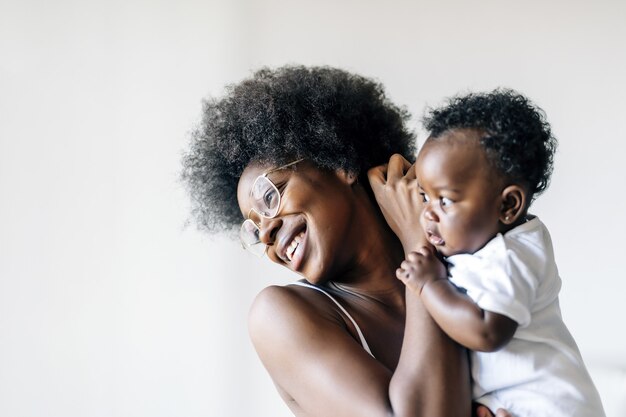 Madre afroamericana cuidando y amando a su bebé sobre un fondo blanco.