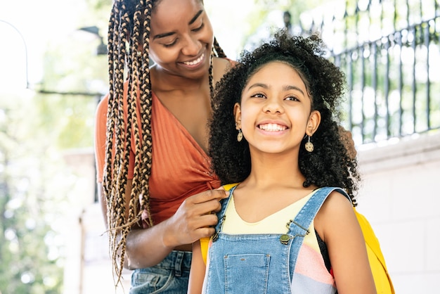 Madre afroamericana llevando a su hija a la escuela. Concepto de educación.