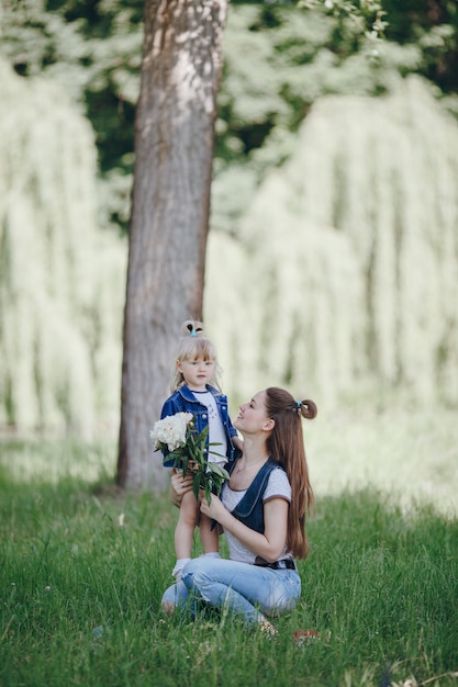 Madre agachada con su hija pequeña con un ramo de flores