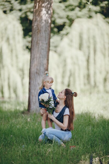 Madre agachada con su hija pequeña con un ramo de flores