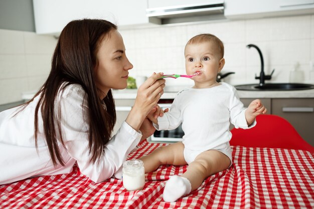 Madre alimenta lindo bebé yogur con cuchara