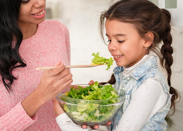 Madre alimentando ensalada hija