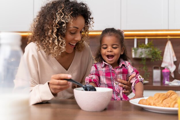 Madre alimentando a su hija en la cocina