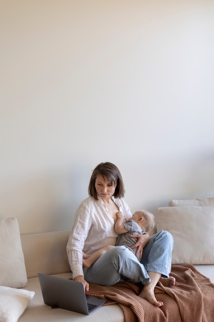 Foto gratuita madre amamantando a su hijo mientras trabaja