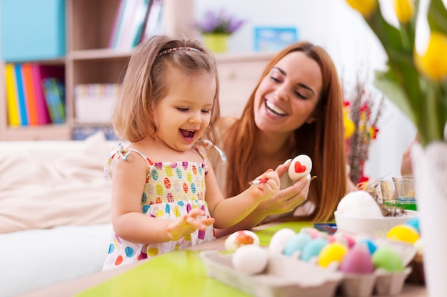 Madre amorosa y su bebé pintando huevos de pascua