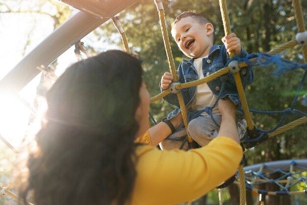 Madre de ángulo bajo y niño feliz en el parque