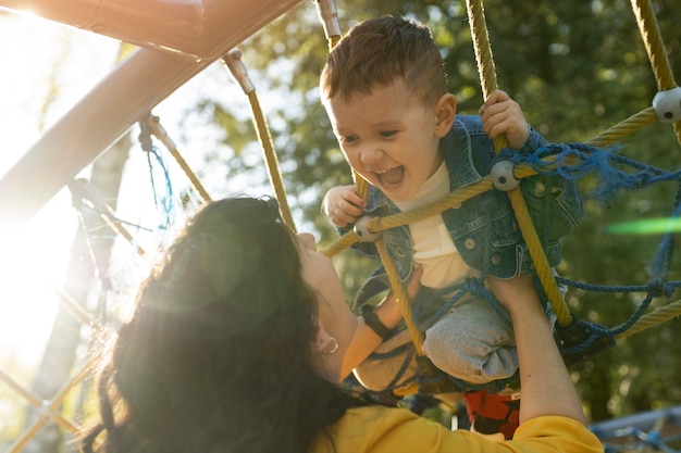 Madre de ángulo bajo y niño feliz en el parque