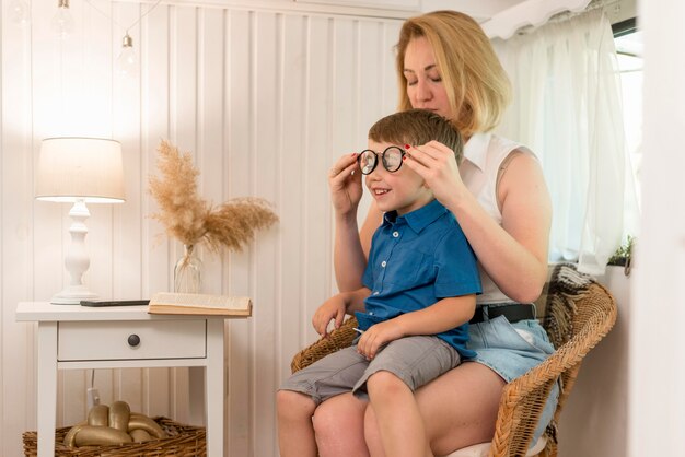 Madre arreglando las gafas de su hijo