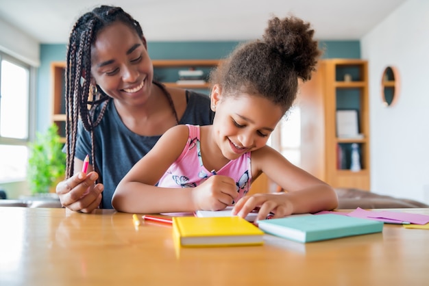 Madre ayudando y apoyando a su hija con la educación en el hogar mientras se queda en casa. Nuevo concepto de estilo de vida normal.