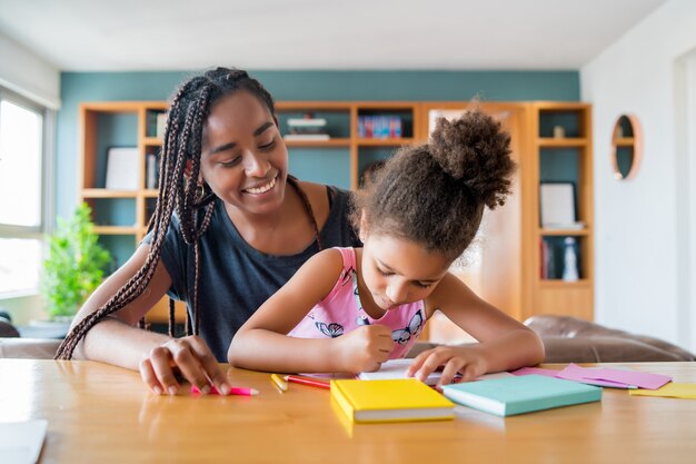 Madre ayudando y apoyando a su hija con la educación en el hogar mientras se queda en casa. Nuevo concepto de estilo de vida normal.