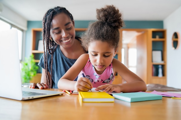 Madre ayudando y apoyando a su hija con la escuela en línea mientras se queda en casa. Nuevo concepto de estilo de vida normal. Concepto monoparental.