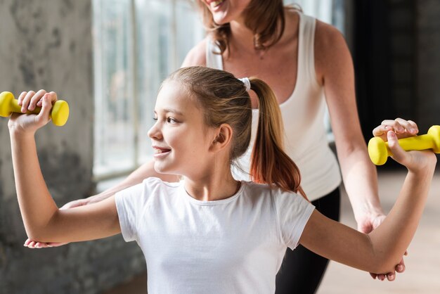 Foto gratuita madre ayudando a hija sosteniendo pesas