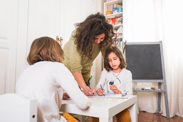 Madre ayudando a hijas con dibujos