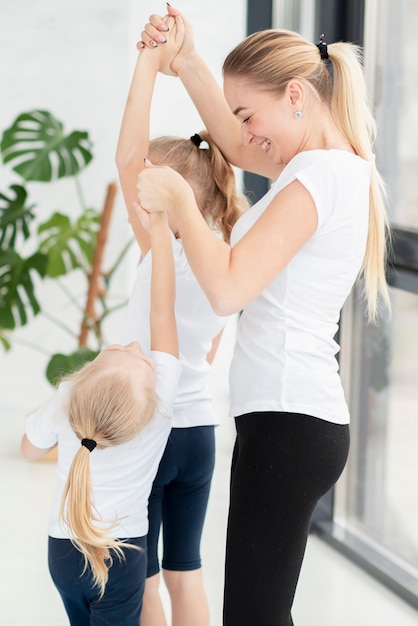 Madre ayudando a hijas a hacer ejercicio en casa