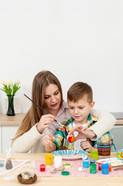 Madre ayudando a hijo a pintar huevos