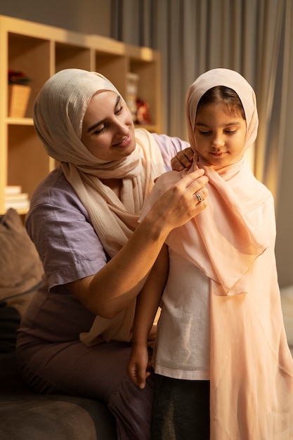 Madre ayudando a niña con hijab vista frontal