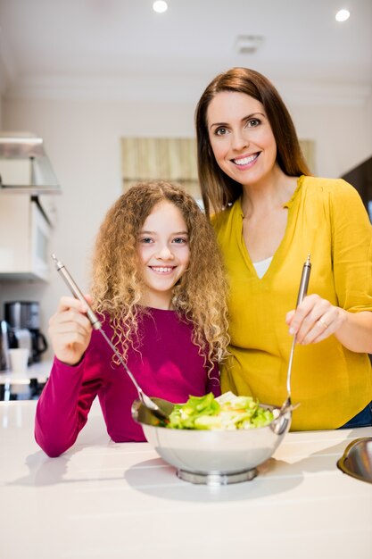 Madre ayudando a su hija en hacer la ensalada