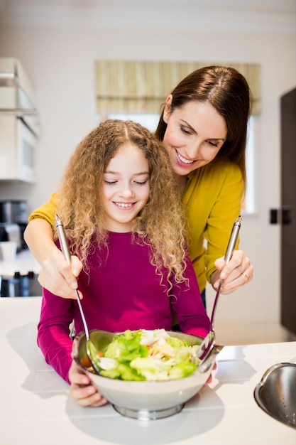 Madre ayudando a su hija en hacer la ensalada