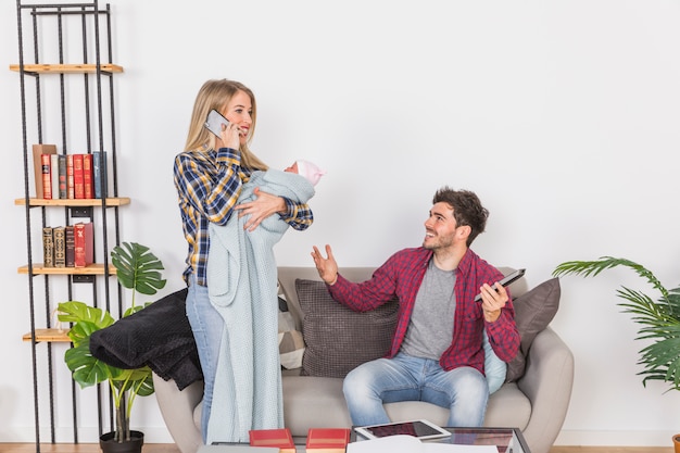 Madre con bebé hablando por teléfono cerca de padre alegre