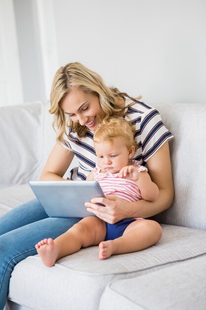 Madre y bebé que usa la tableta digital de