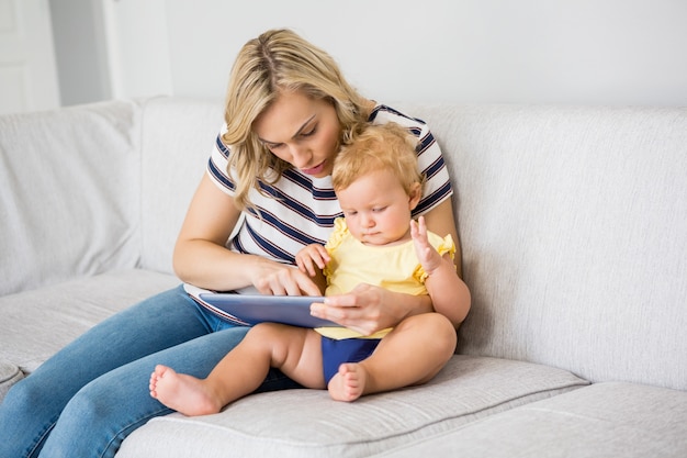 Madre y bebé que usa la tableta digital de