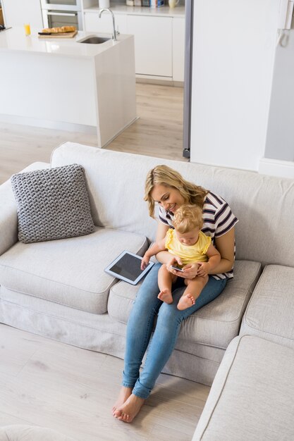 Madre y bebé que usa el teléfono móvil