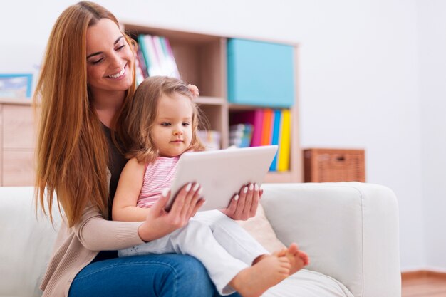 Madre con bebé mediante tableta digital en casa