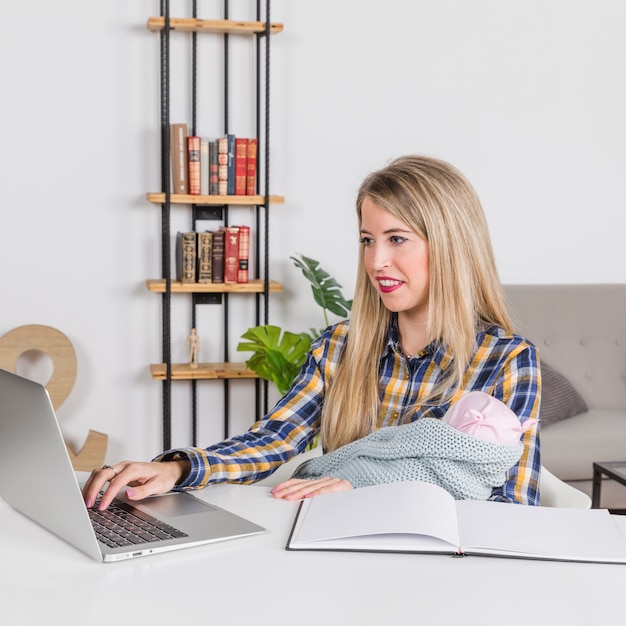 Foto gratuita madre con bebé trabajando con laptop en casa