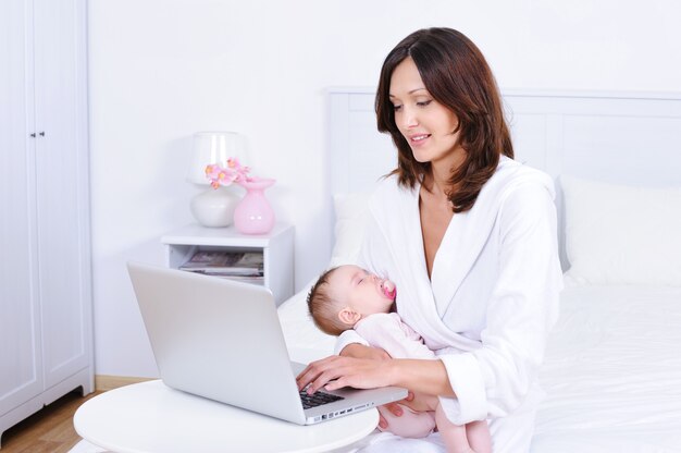 Madre con bebé usando laptop en habitación