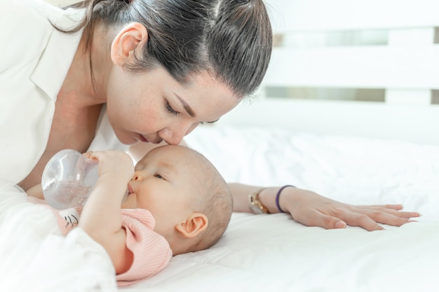 Madre besando a un bebé que está bebiendo de una botella