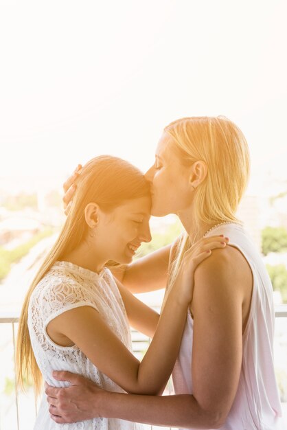 Madre besando a su hija en la frente