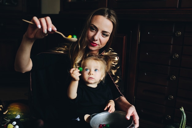 Madre con caramelos en una cuchara mientras su hija mira