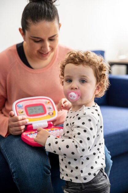 Madre en casa sentada en el sofá y jugando con el niño