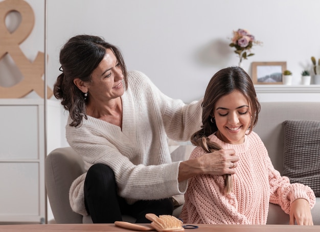 Madre en casa trenzando cabello niña