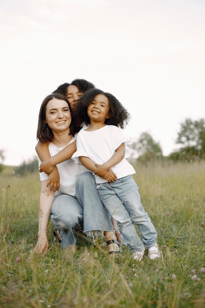 Madre caucásica y sus dos hijas afroamericanas abrazándose juntos al aire libre