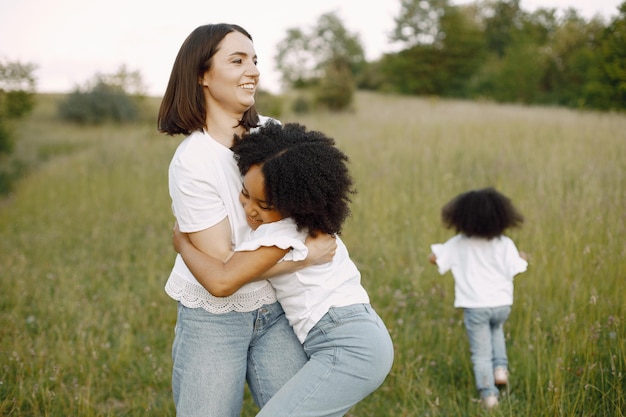 Madre caucásica y sus dos hijas afroamericanas abrazándose juntos al aire libre