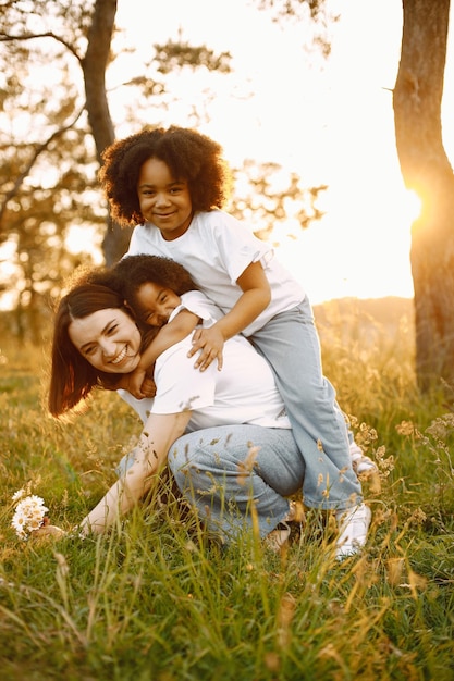 Madre caucásica y sus dos hijas afroamericanas abrazándose juntos al aire libre