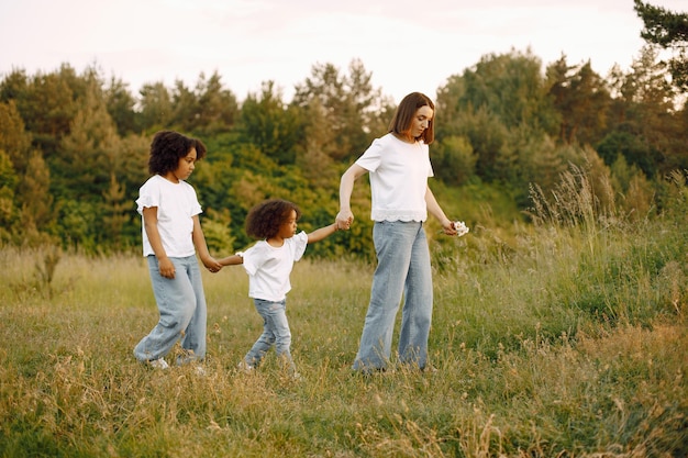 Madre caucásica y sus dos hijas afroamericanas caminando juntos al aire libre